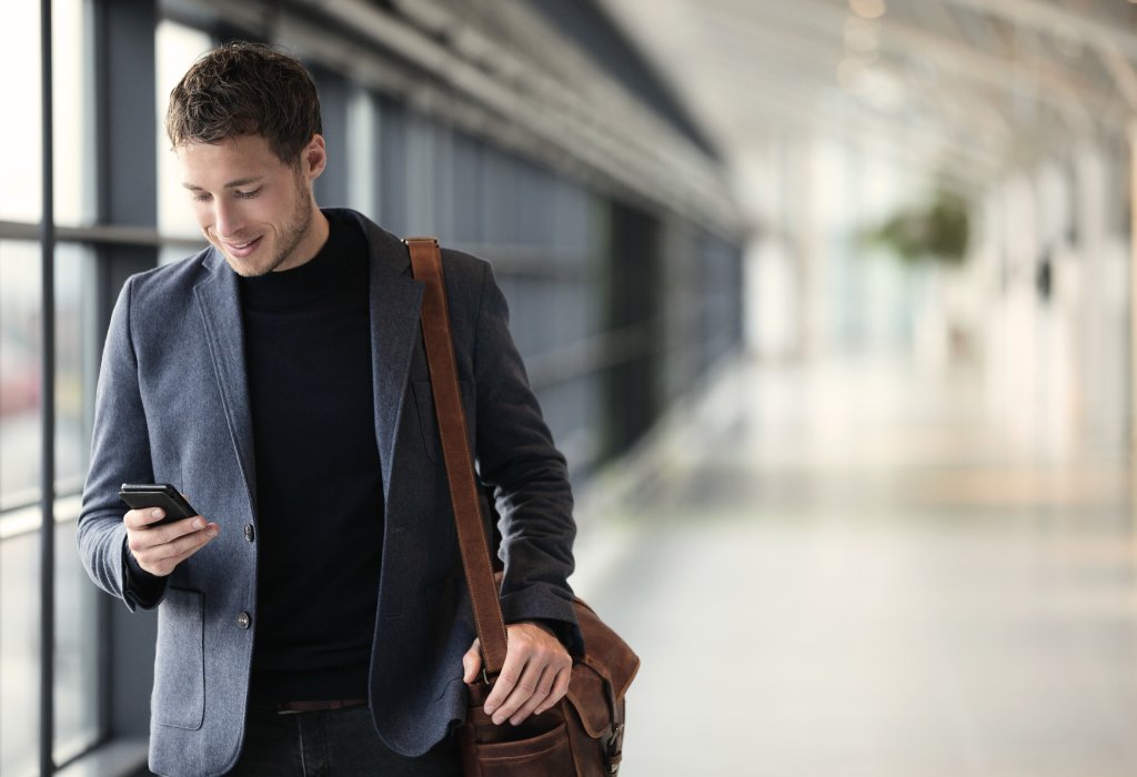 Man walking down hallway looking at his phone